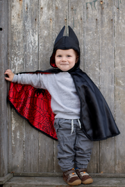 Child wearing reversible superhero cape with black exterior and red interior with web pattern