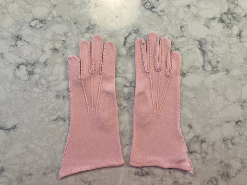 Light pink gloves with decorative stitching on marble background