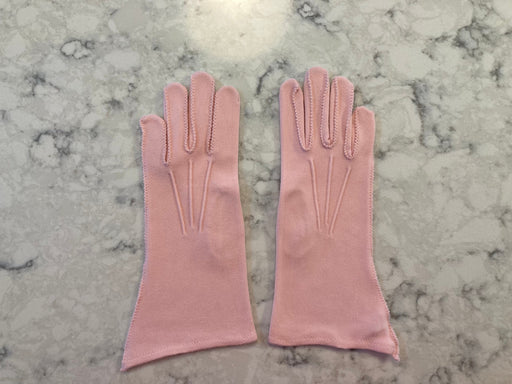 Light pink gloves with decorative stitching on marble background
