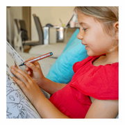 Young girl in red shirt using orange Magic Tri Stix marker to color or draw