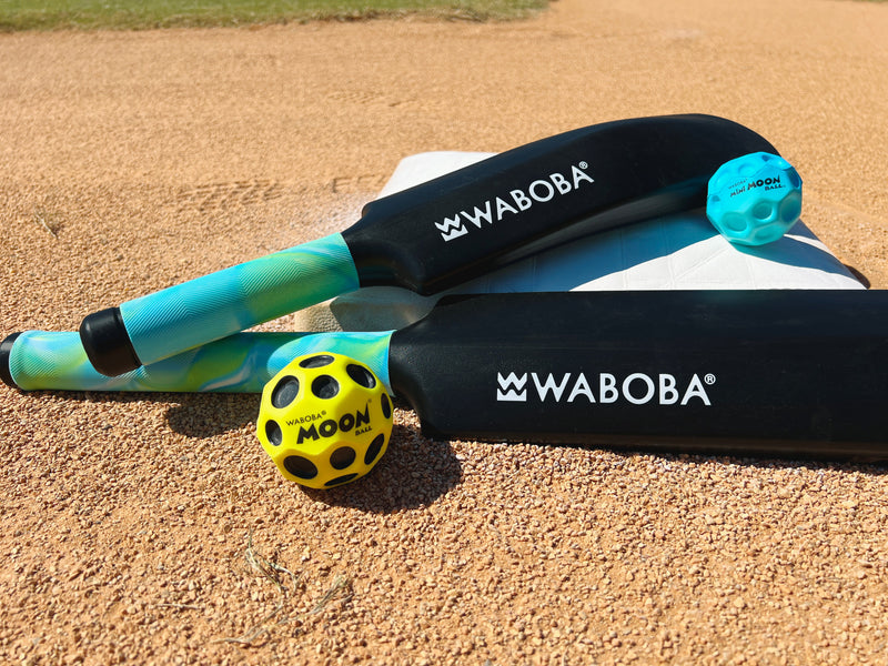 Waboba cricket set with bat, yellow and blue moon balls on sandy surface