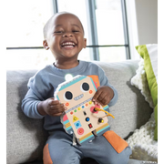Happy child playing with colorful Blinkity Bot educational toy on couch