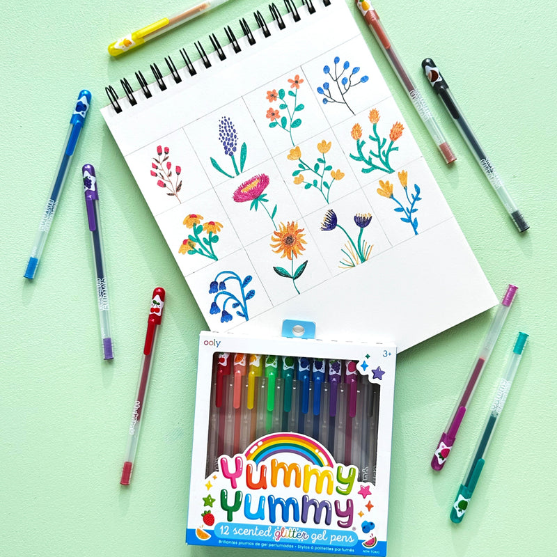 OOLY Yummy Yummy scented glitter gel pens with colorful flower drawings on notebook