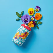 Decorative tin can with pansy flowers growing from top on blue background