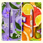 Two scented lava pens with purple and orange liquid surrounded by flowers and citrus fruits