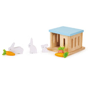 Wooden rabbit hutch with blue roof and white rabbit figures with carrots