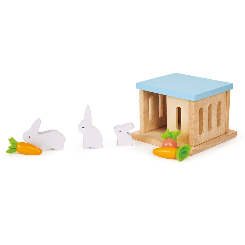Wooden rabbit hutch with blue roof and white rabbit figures with carrots