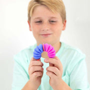 Child holding blue and pink Krumples fidget toy showing bendable accordion design