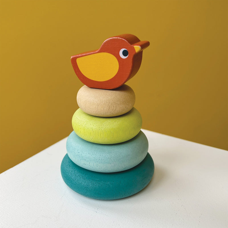 Colorful wooden stacking toy with teal, blue, green, natural rings topped with orange bird