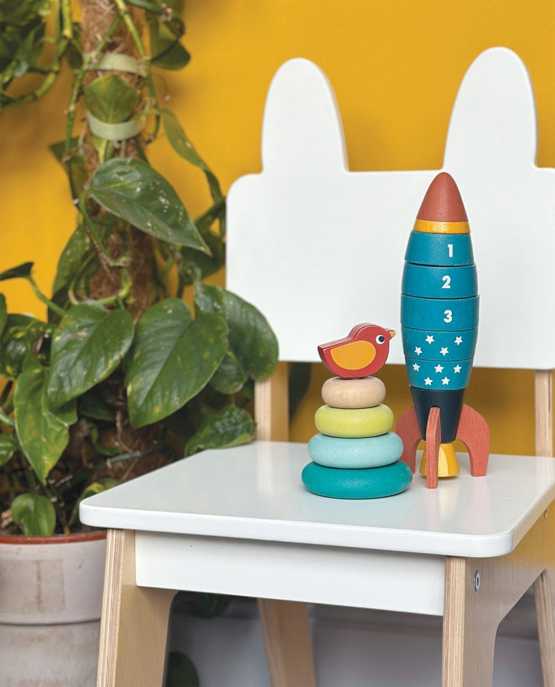Mentari wooden stacking toy with rocket and colorful rings featuring bird on white chair