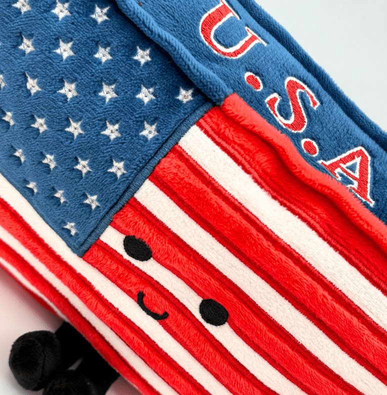 Close-up detail of American flag plush keychain showing embroidered stars, stripes and cute face