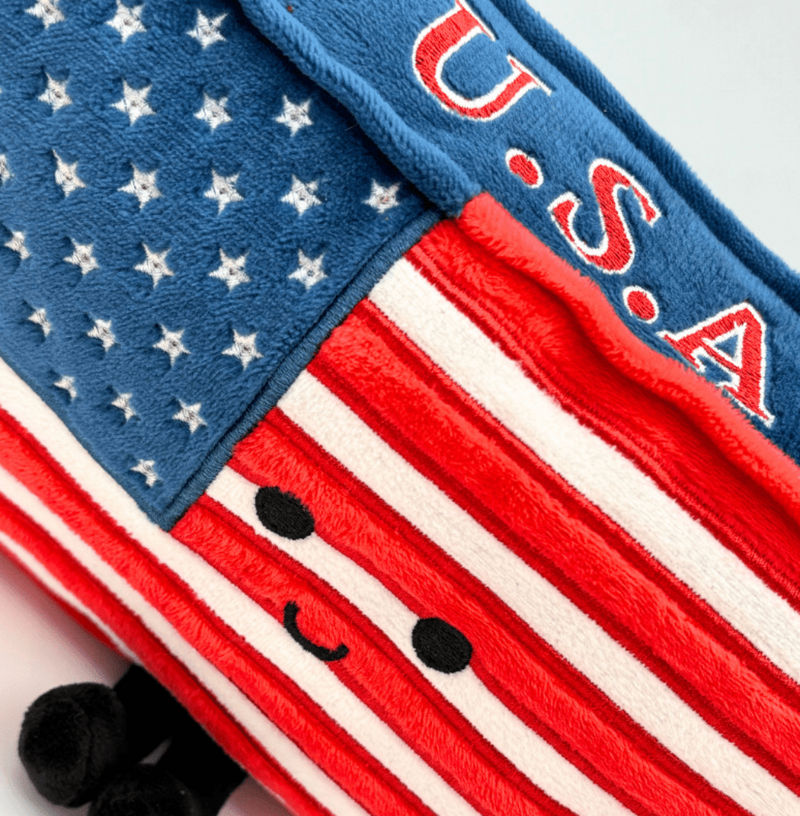Close-up detail of American flag plush toy showing stars, stripes, and cute embroidered face