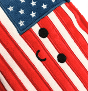Close-up detail of American flag plush with cute embroidered face on red and white stripes