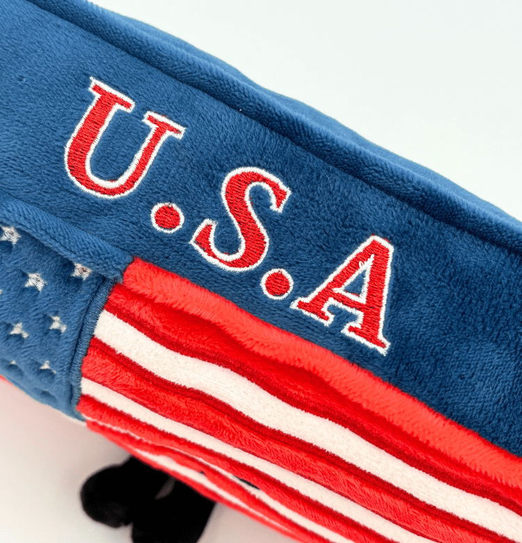 Close-up detail of blue plush USA stuffed product showing embroidered U.S.A text and flag stripes