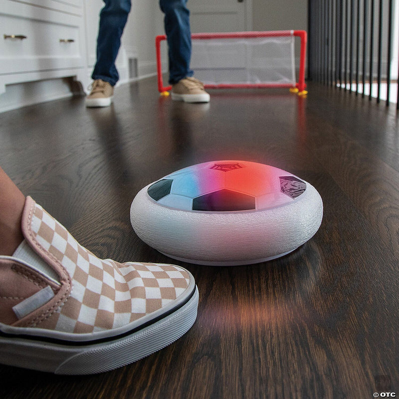 Hover soccer ball with LED lights gliding on dark hardwood floor with goal
