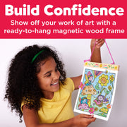 Child proudly displaying completed fairy-themed paint by number artwork in magnetic frame