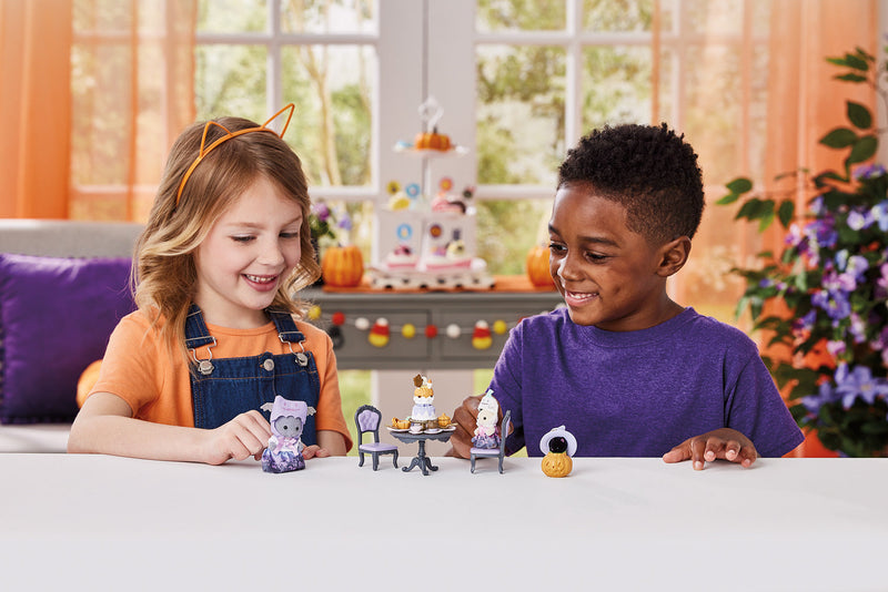 Two children playing with Halloween-themed Calico Critters figurines and furniture set