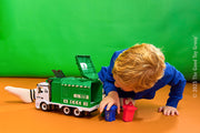 Child playing with green garbage recycling truck toy with light and sound features