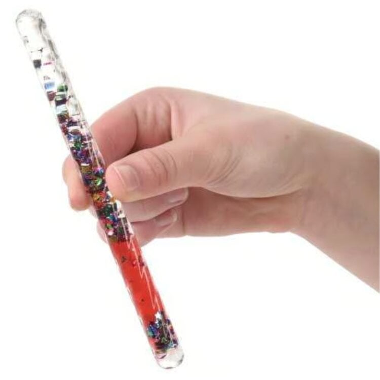 Hand holding clear tube wand filled with colorful glitter and red liquid