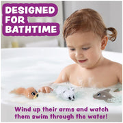 Child playing with wind-up swimming animal toys in bathtub with bubbles