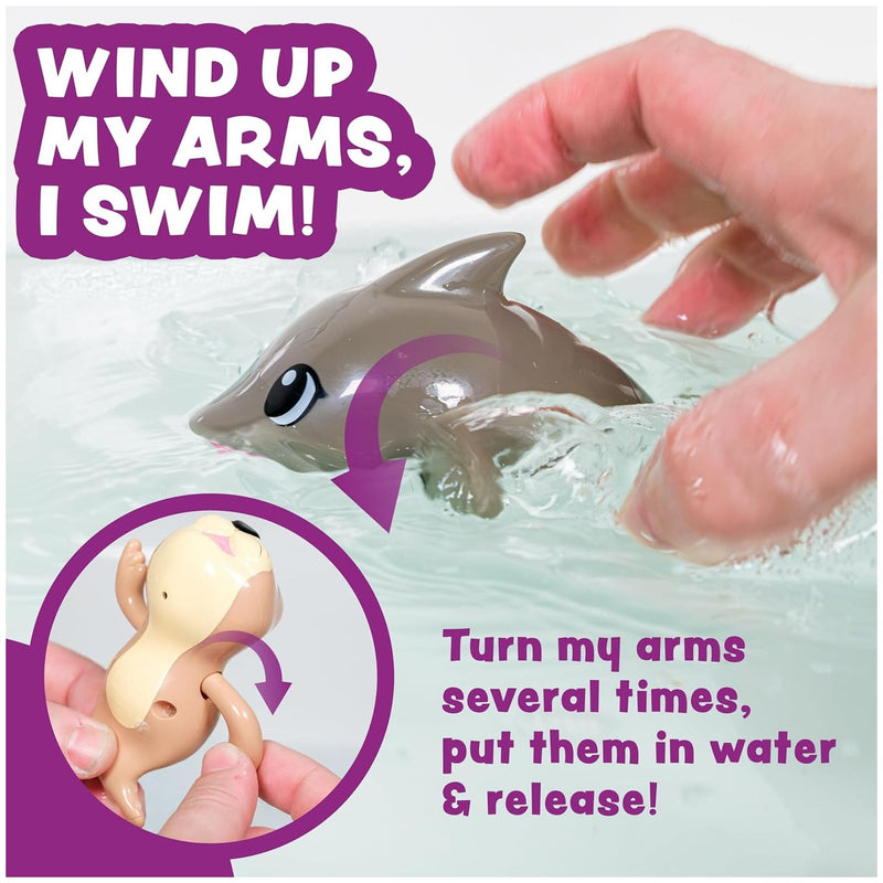 Wind-up swimming dolphin toy being demonstrated in water with hands showing winding mechanism